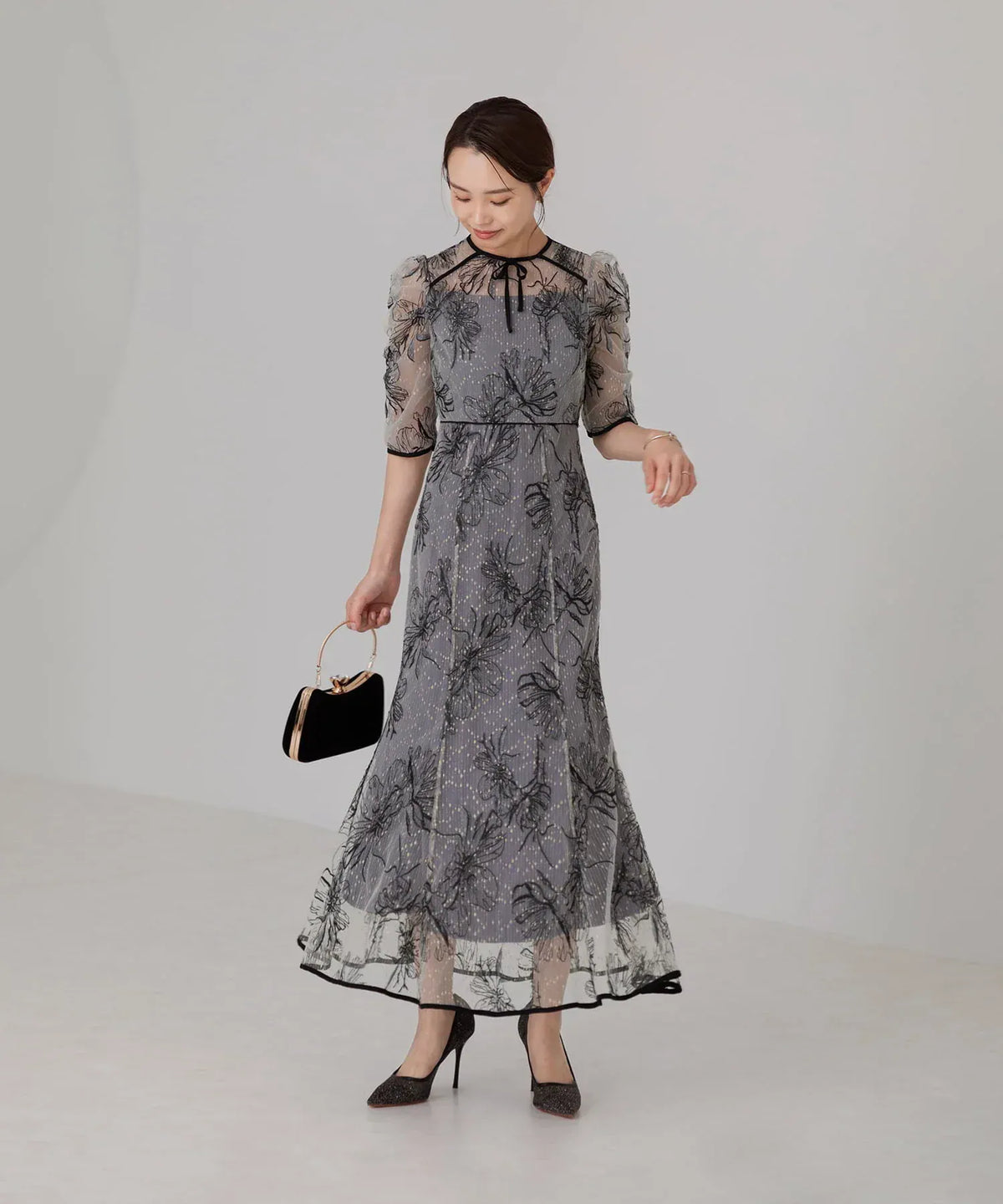 首元の細リボンとパフスリーブが上品な、透け感のある黒の花柄刺繍チュールを重ねたグレーのマーメイドパーティードレスの全身。