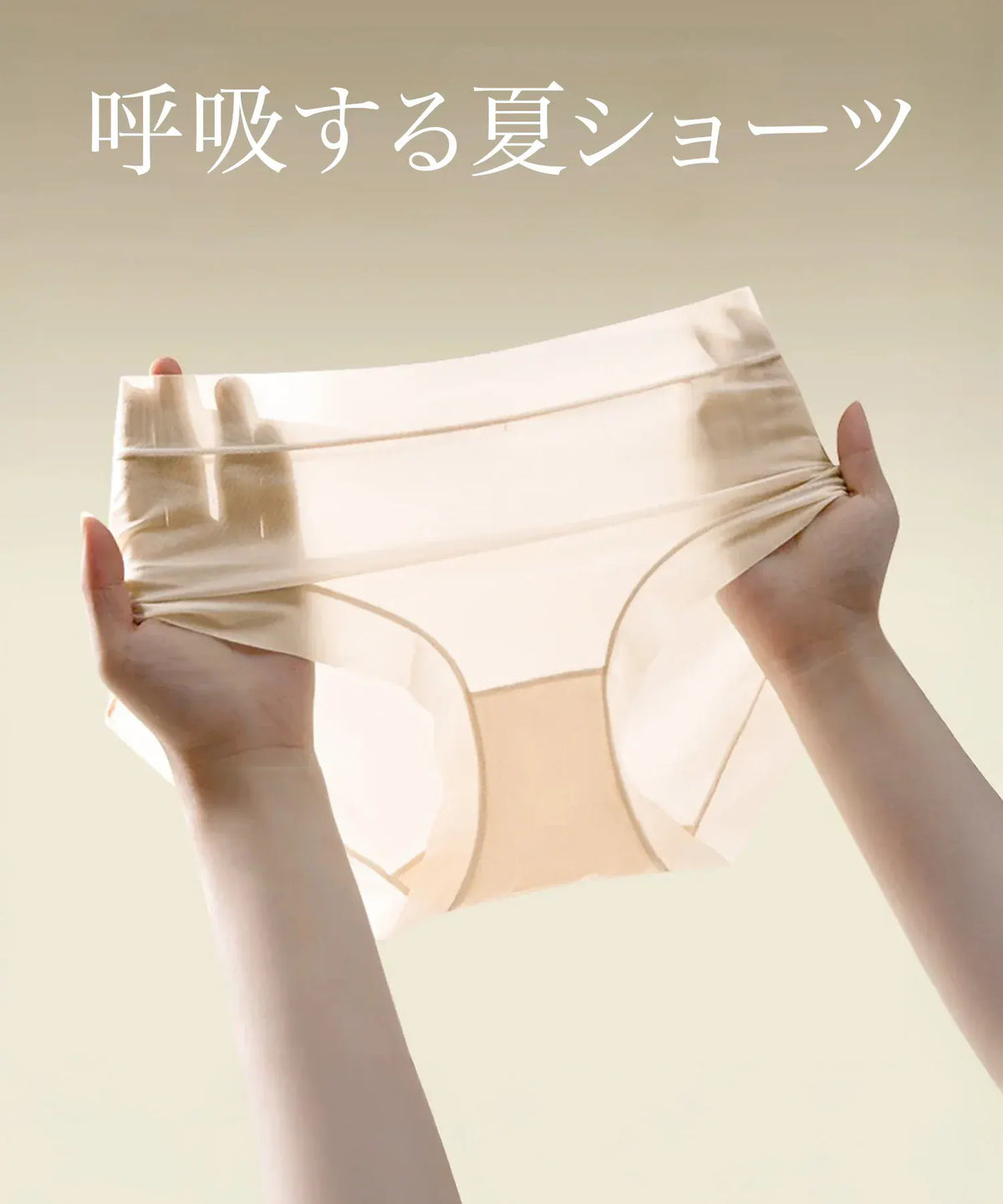 両手で左右に広げられた、指が透けるほど薄手で伸縮性のあるベージュの無地シームレスショーツ。