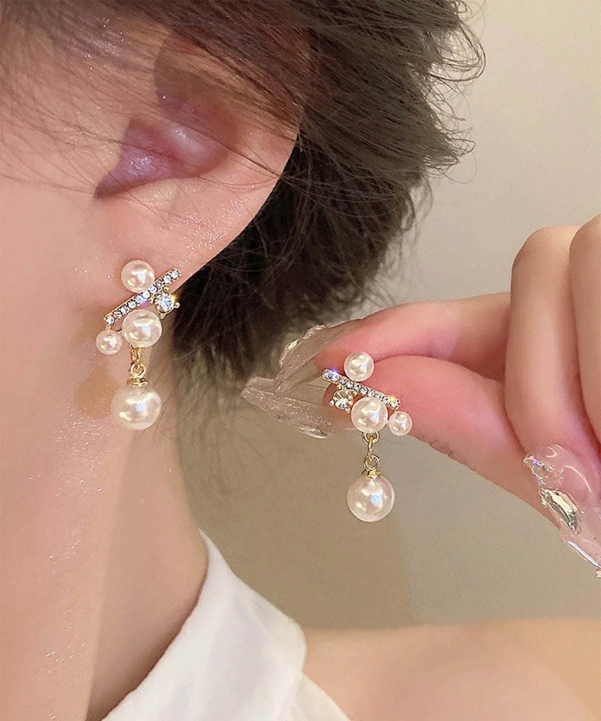 小粒ビジューのバーに上品な艶のパールが揺れる、結婚式やお呼ばれにも映えるパールシルバーストーンピアスの着用イメージ。