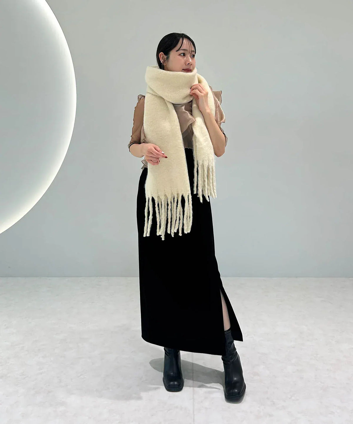 首元にぐるりと巻いてタイトスカートに合わせた、ボリューム感のあるアイボリーのシンプルフリンジマフラーの着こなし。
