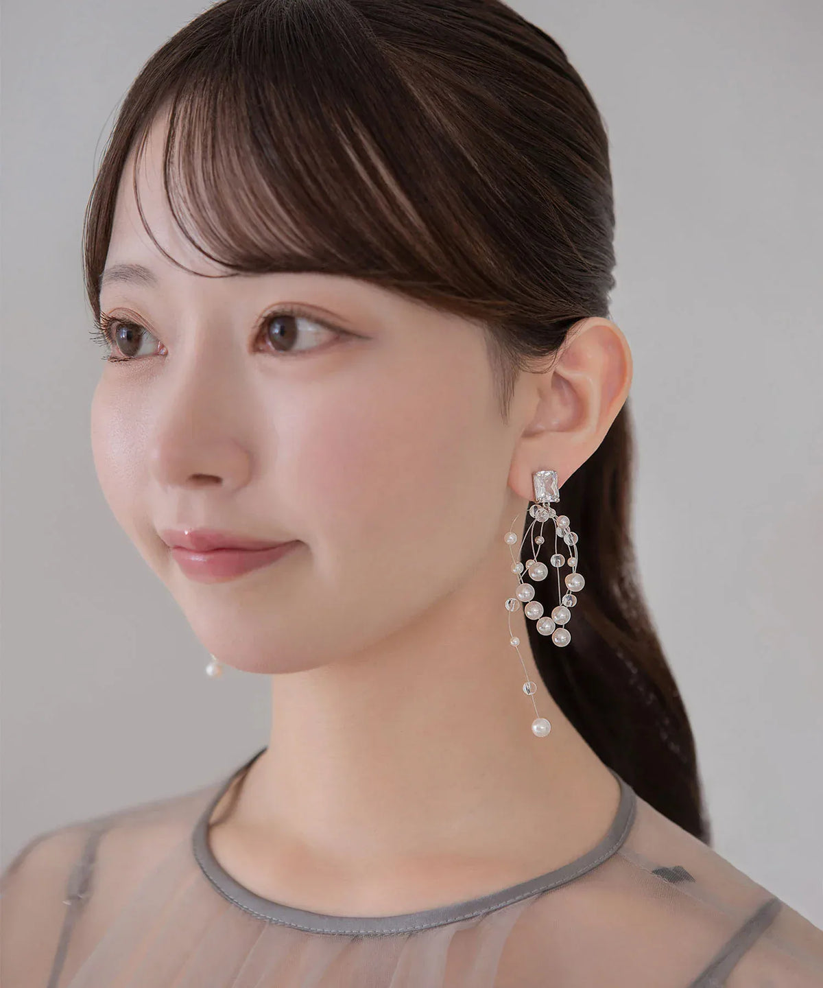 繊細なワイヤーに小粒パールとクリアビーズが揺れるモチーフが付いたシルバー系ロングピアスの着用アップ。