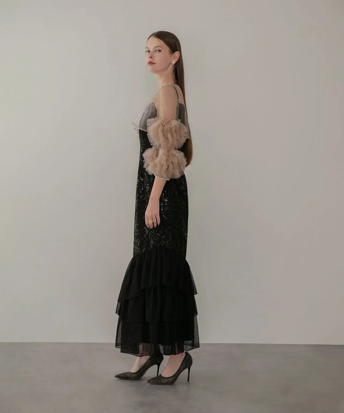 ベージュのチュールフリル袖と黒のティアード裾が引き立つスパンコールロングワンピースの横から見たシルエット