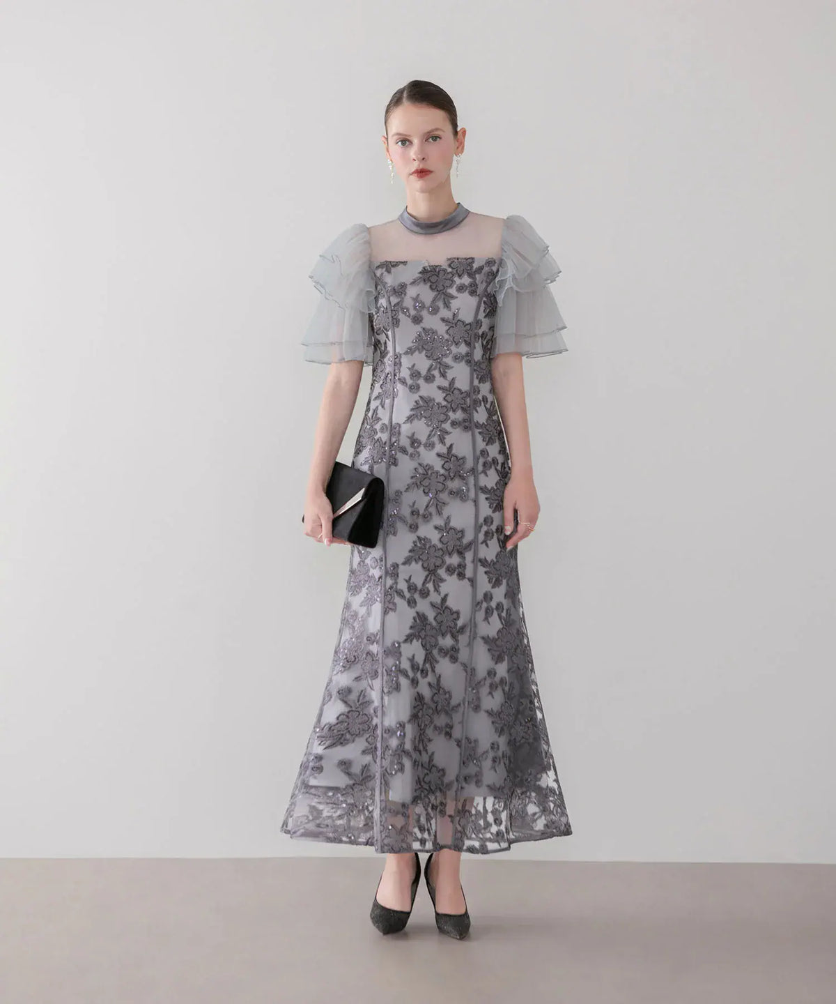 透け感のあるハイネックとチュールフリル袖に花柄スパンコール刺繍が華やかなグレーのマーメイドワンピースドレスの全身。
