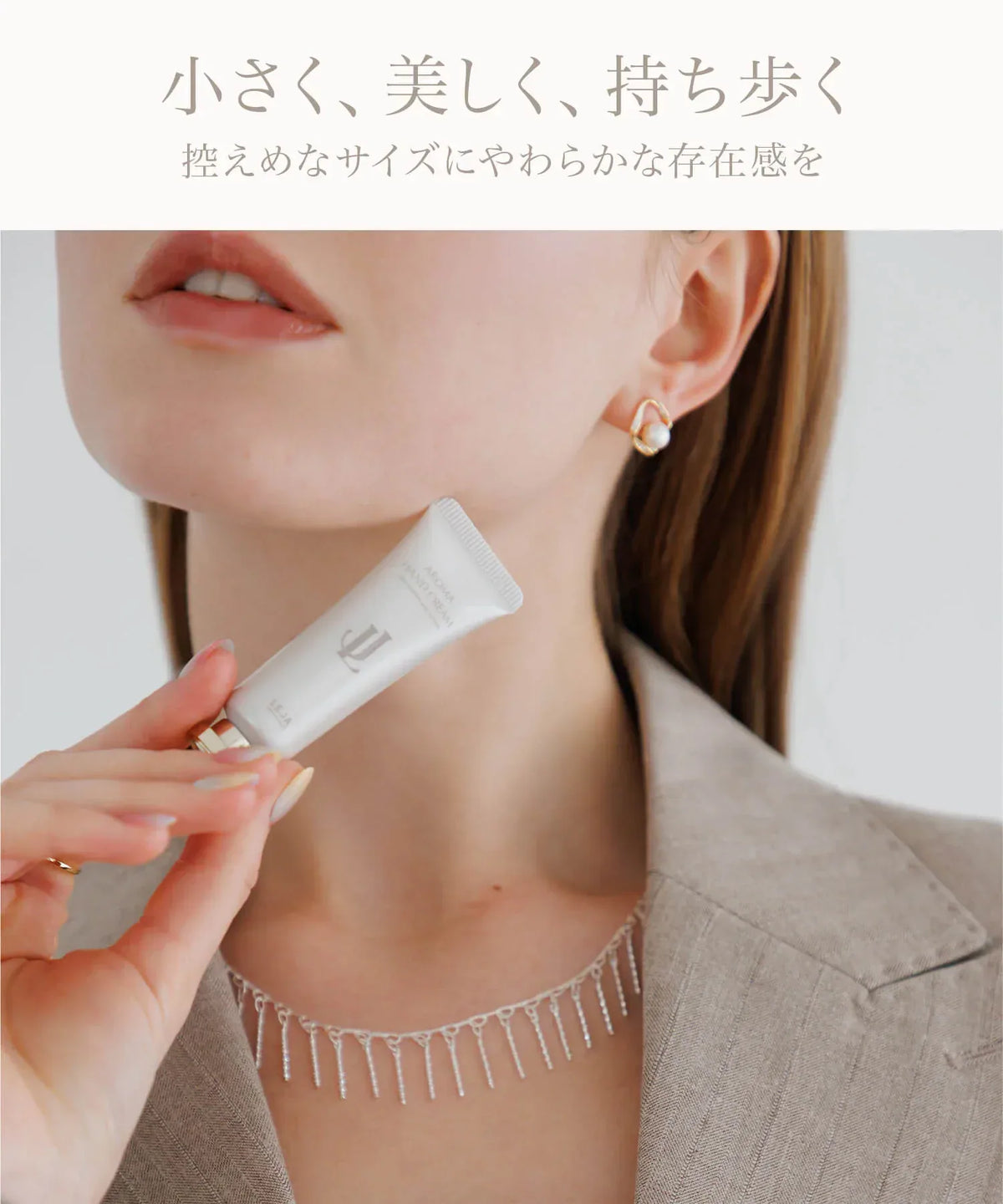 あご下に添えて持ち歩きやすいコンパクトなサイズ感を表現したホワイトのミニハンドクリームの手元アップ