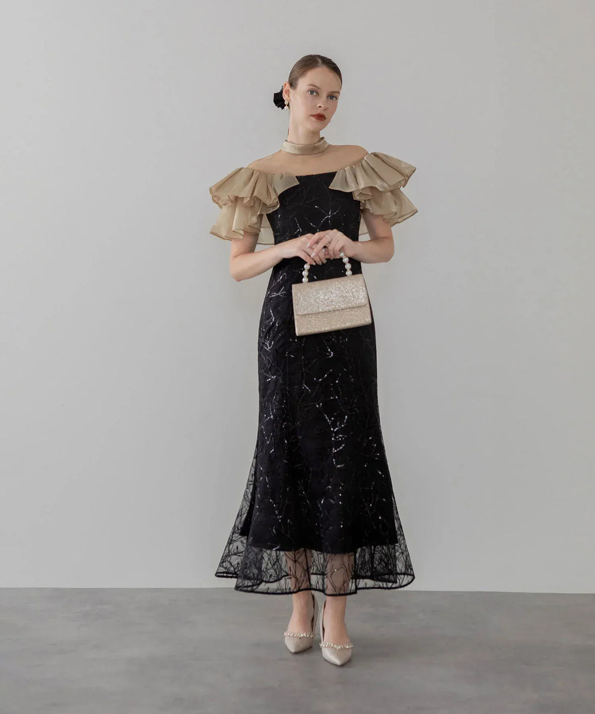 ベージュのフリル袖とスパンコール刺繍が華やかな、結婚式のお呼ばれにおすすめの黒のマーメイドオケージョンドレス。
