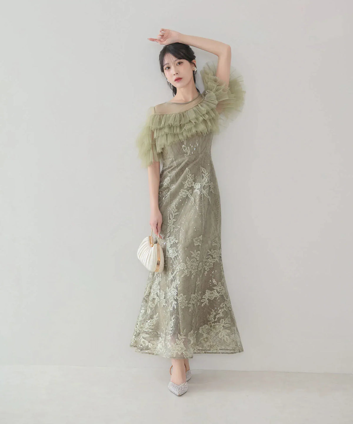 胸元のアシンメトリーなチュールフリルと花柄スパンコール刺繍が上品にきらめくオリーブグリーンのマーメイドオケージョンドレスの全身スタイル。