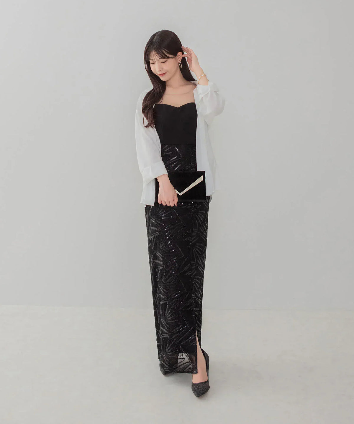 白のシアーシャツを羽織りクラッチバッグを合わせたスパンコール刺繍スリット入りブラックイブニングドレスの着こなし例