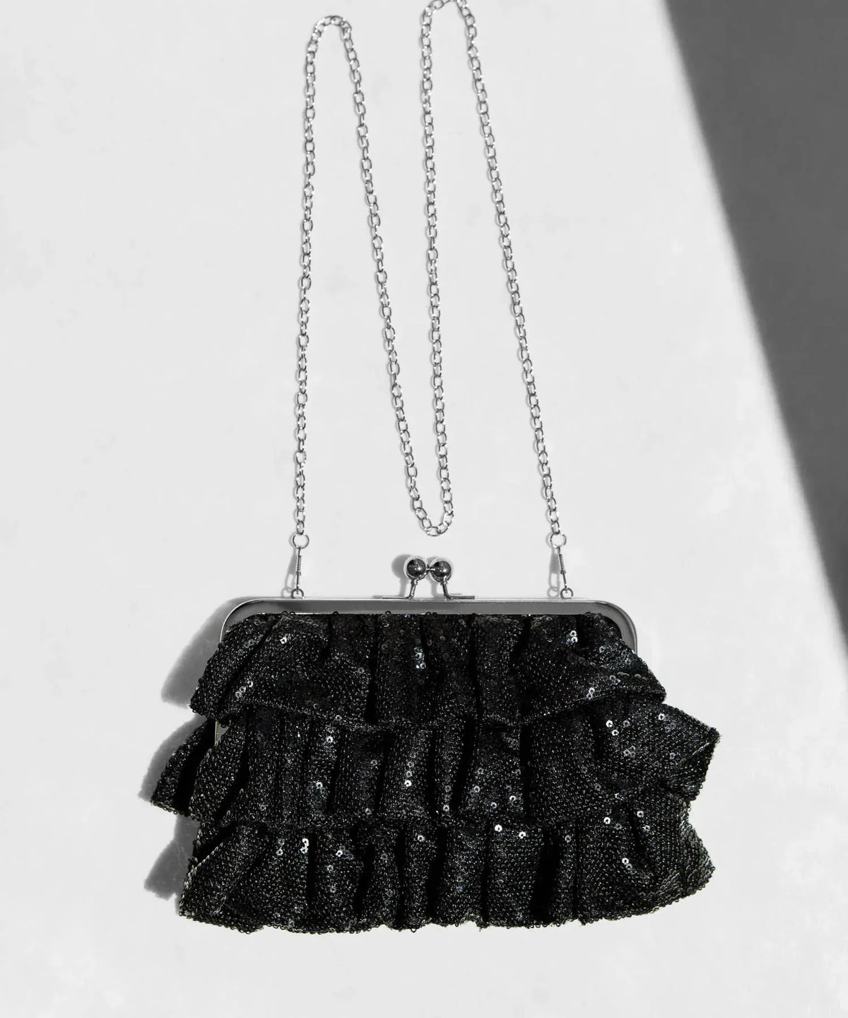 煌めく黒のスパンコールフリルとシルバーのがま口金具にチェーンストラップが付いたパーティーバッグの正面置き姿