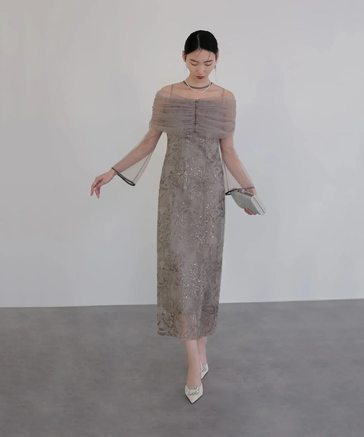 透け感のあるチュールオフショルダーと花柄刺繍が上品な、モカグレーのIラインオケージョンドレスの全身スタイル。
