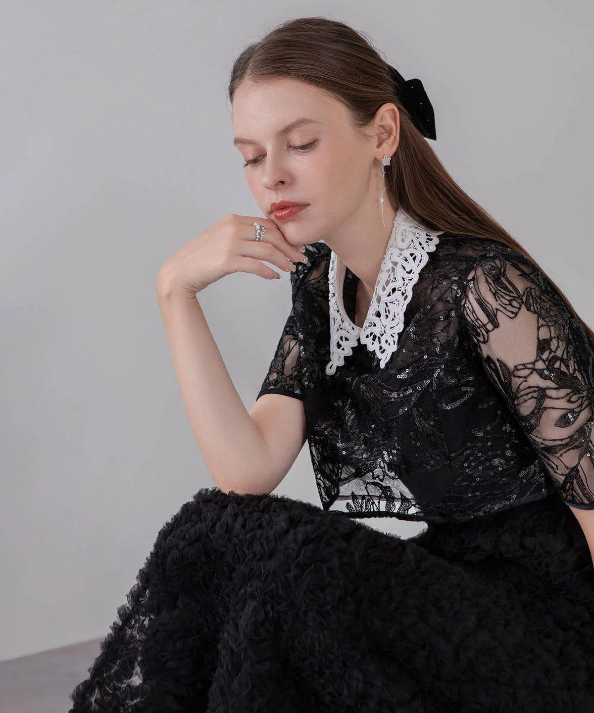 白いレースカラーとスパンコール刺繍が華やかに輝く黒のシアートップスを着用した、結婚式にもおすすめなオケージョンドレスの上半身アップ。