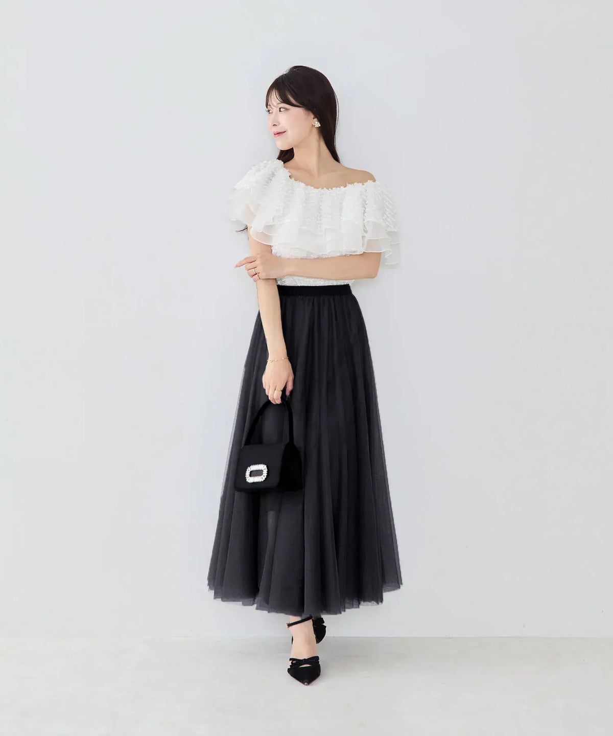 黒のチュールロングスカートに合わせた、白のフリルが華やかなオフショルダートップスのコーディネート。