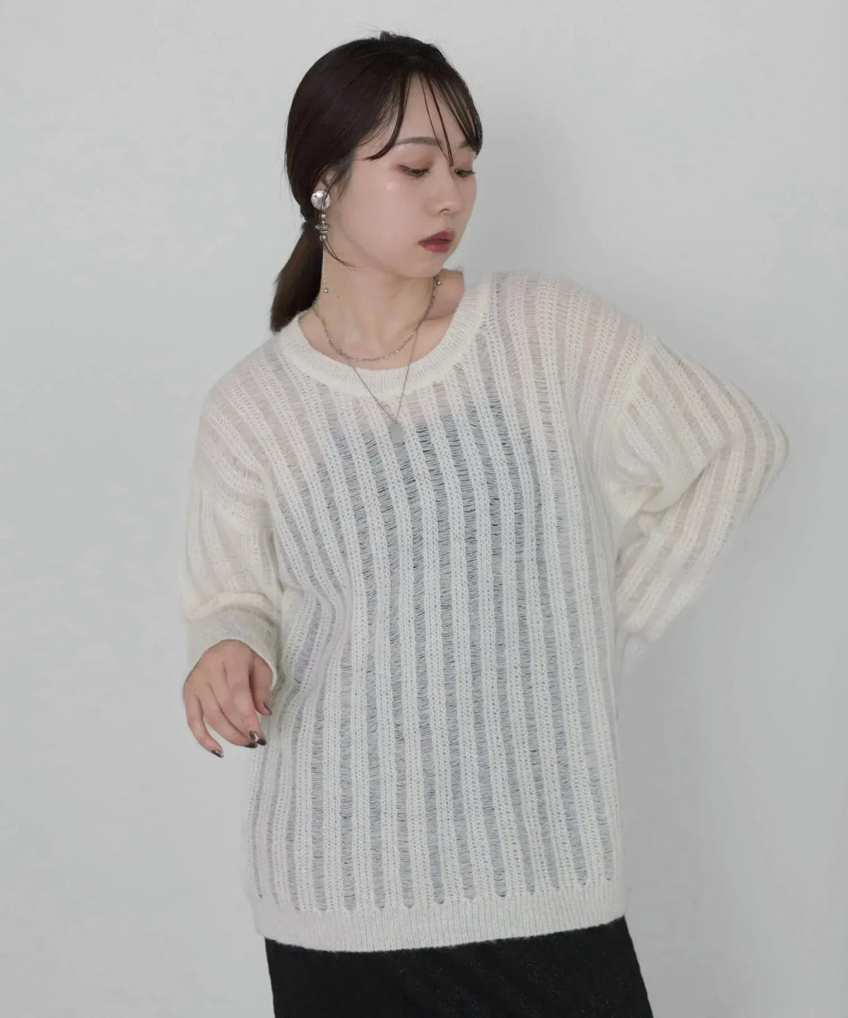 透け感のある縦編み模様とゆったりしたクルーネックが特徴的な白のメッシュプルオーバーニットトップス。