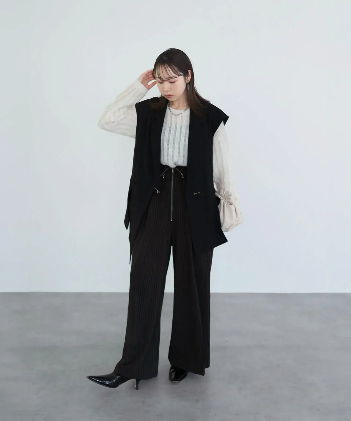 黒のロングジレとワイドパンツにホワイトをレイヤードした、透け感がおしゃれなメッシュプルオーバーニットトップスの着こなし。
