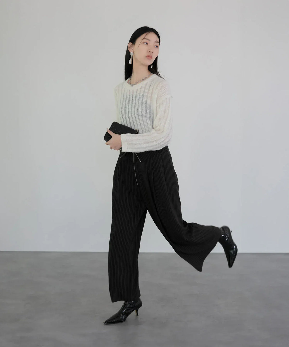 黒のワイドパンツと合わせた白の透け感あるメッシュプルオーバーニットトップスの全身コーデ