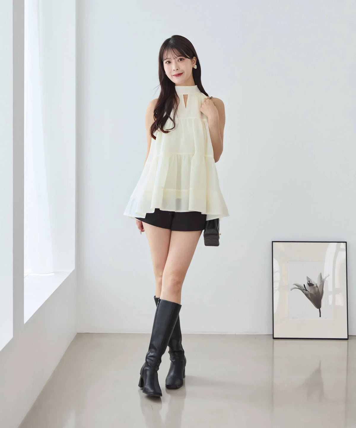 ショートパンツとロングブーツを合わせた白の2WAYリボンアメスリティアードシアートップスの全身コーディネート