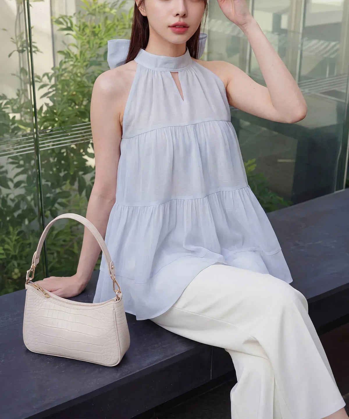 白のワイドパンツに合わせた、首元のスリットとふんわり広がるティアードシルエットが涼しげなライトブルーのアメスリシアートップスの着こなし。