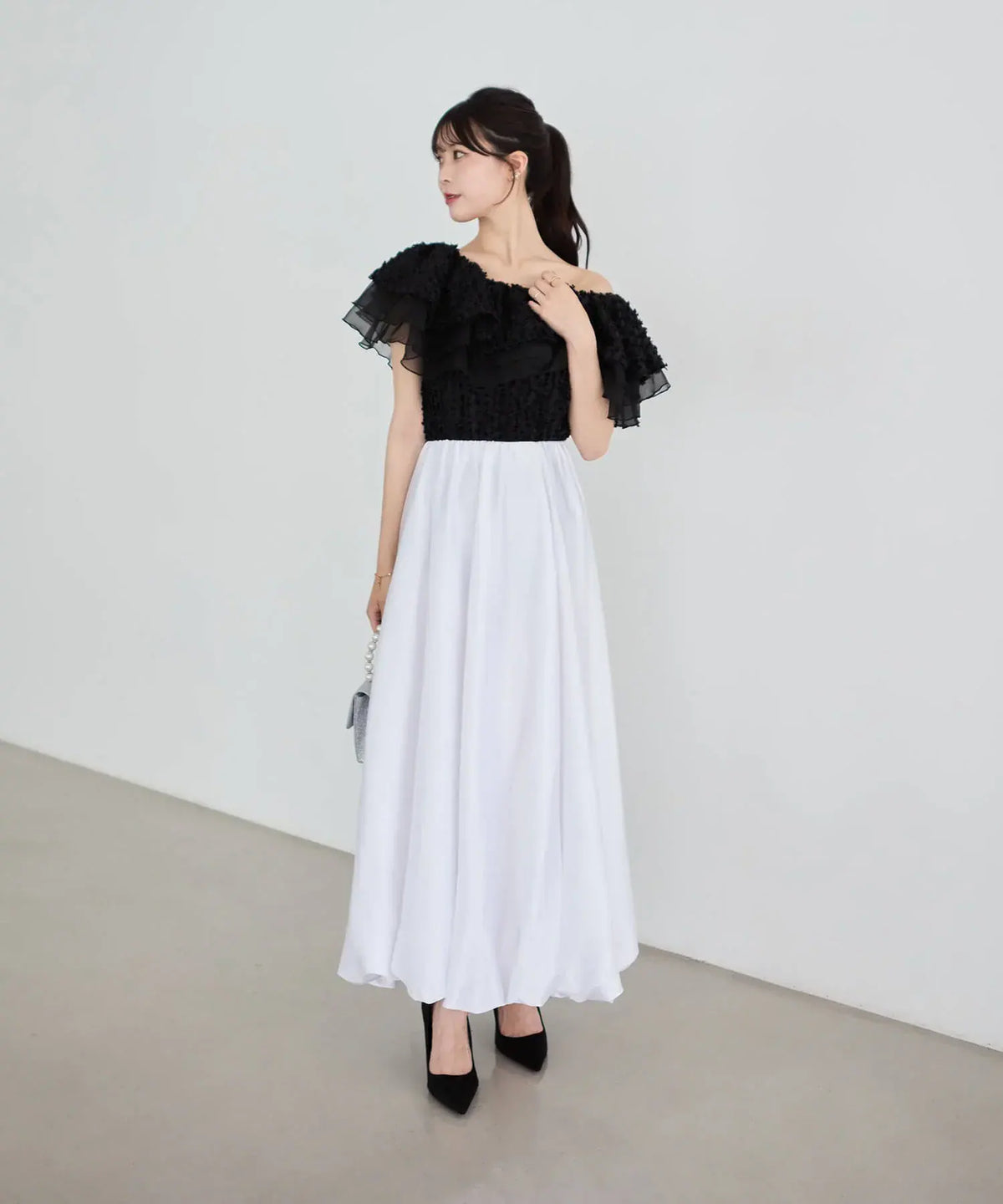 黒のフリル付きオフショルに白のロングスカートを合わせた、3WAYオフショルフリンジシアーレイヤードトップスの全身コーディネート。