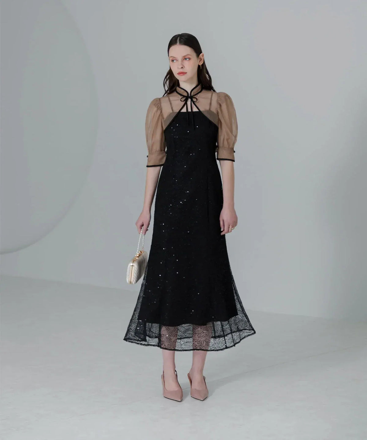 スパンコールが輝く黒のマーメイドドレスに、ベージュのシースルーボレロを合わせた結婚式向けオケージョンワンピース。