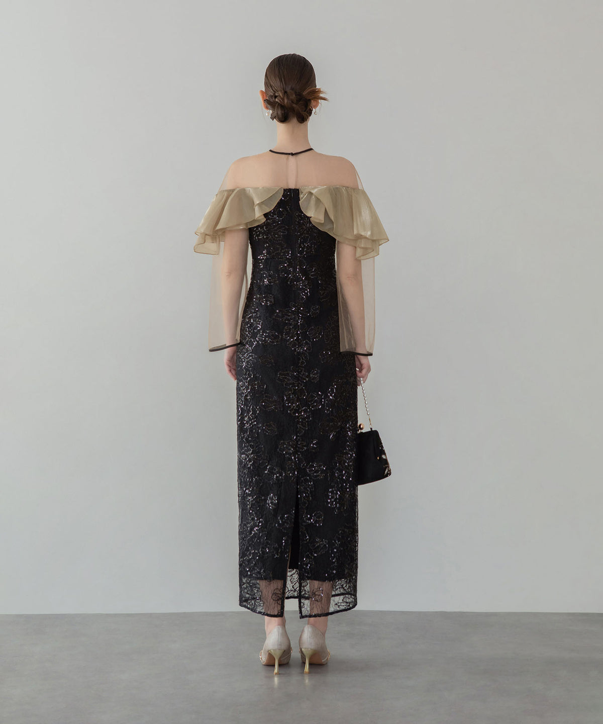 ベージュのシフォンフリルと煌めくスパンコール刺繍が華やかな、黒のIラインロング丈オケージョンドレスの後ろ姿。